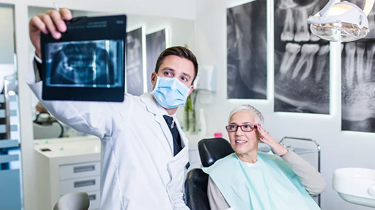 Mulher vendo radiografia bucal junto com o dentista