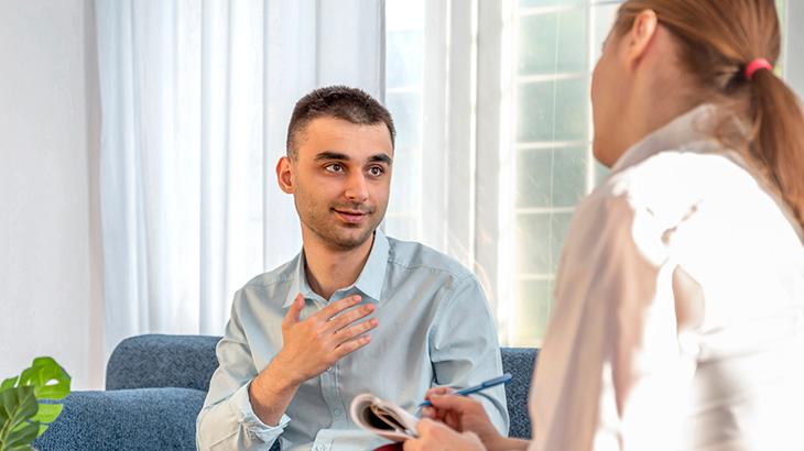 Homem sentado em conversando, em consulta, com psicóloga